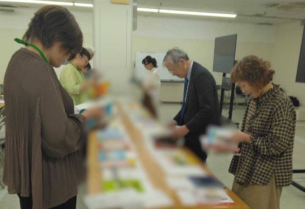 選書会議の様子 - たくさんの絵本が並ぶテーブルで選考中